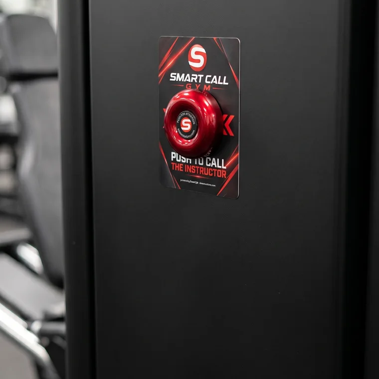 Red Smart Call push button mounted on a gym machine